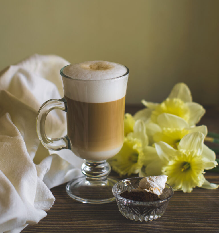 a glass of foamy latte decorated with daffodil